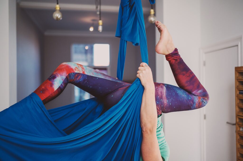 woman in galaxy leggings performing aerial yoga for the manzanilla sophia blog