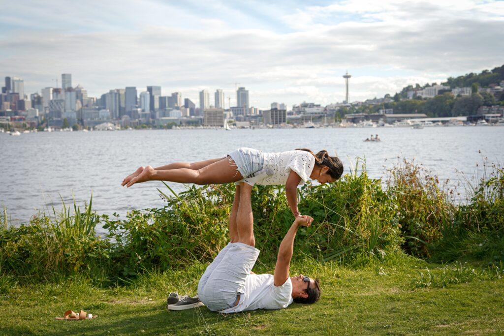 couple performing acro yoga by lake for the manzanilla sophia blog