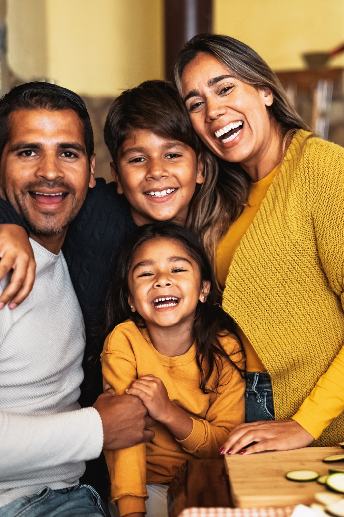 Family hugging wearing same colors and smiling at camera